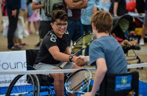 two wheelchair tennis players shaking hands after a game